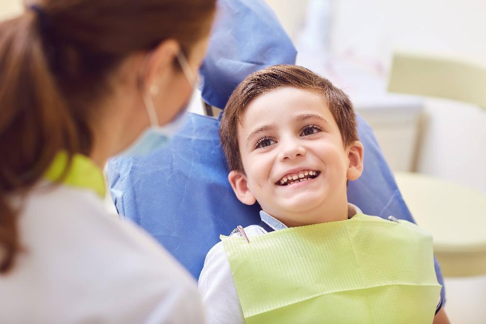 young boy smiling in dental exam chair l pediatric dentist wilmington de