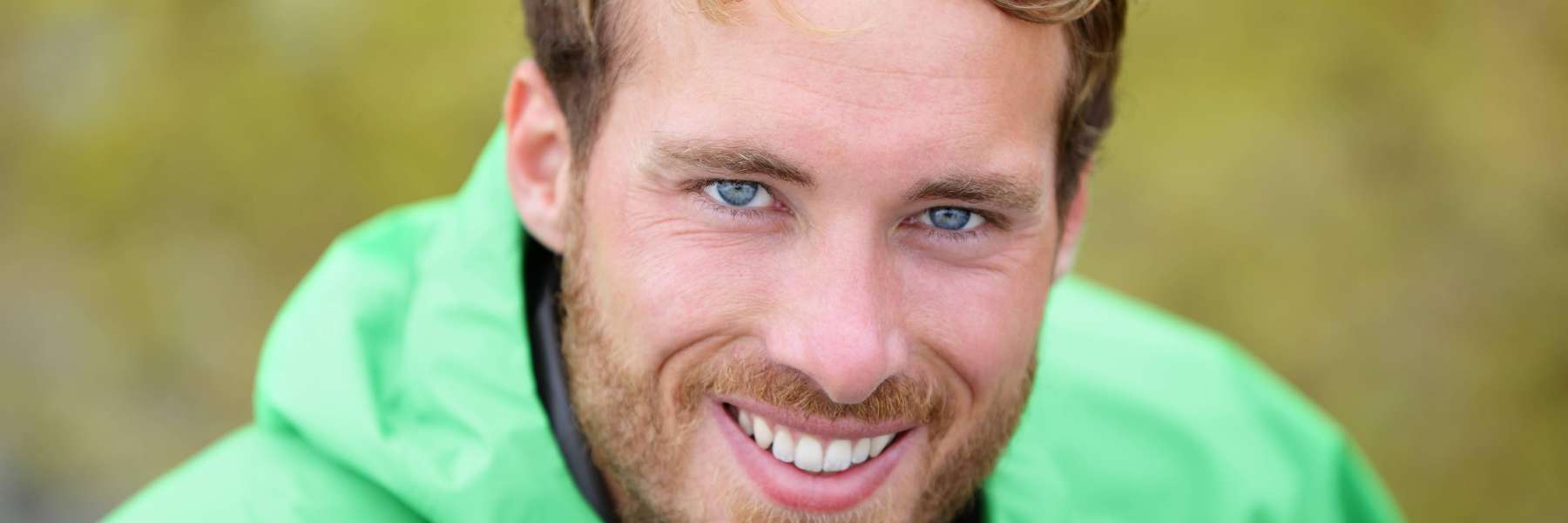 A smiling man in green at the park
