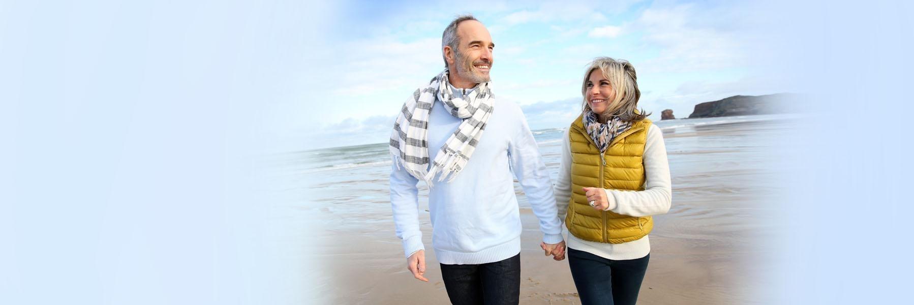 older couple smiling walking on a beach l Drs. Gladnick and Justison pike creek de