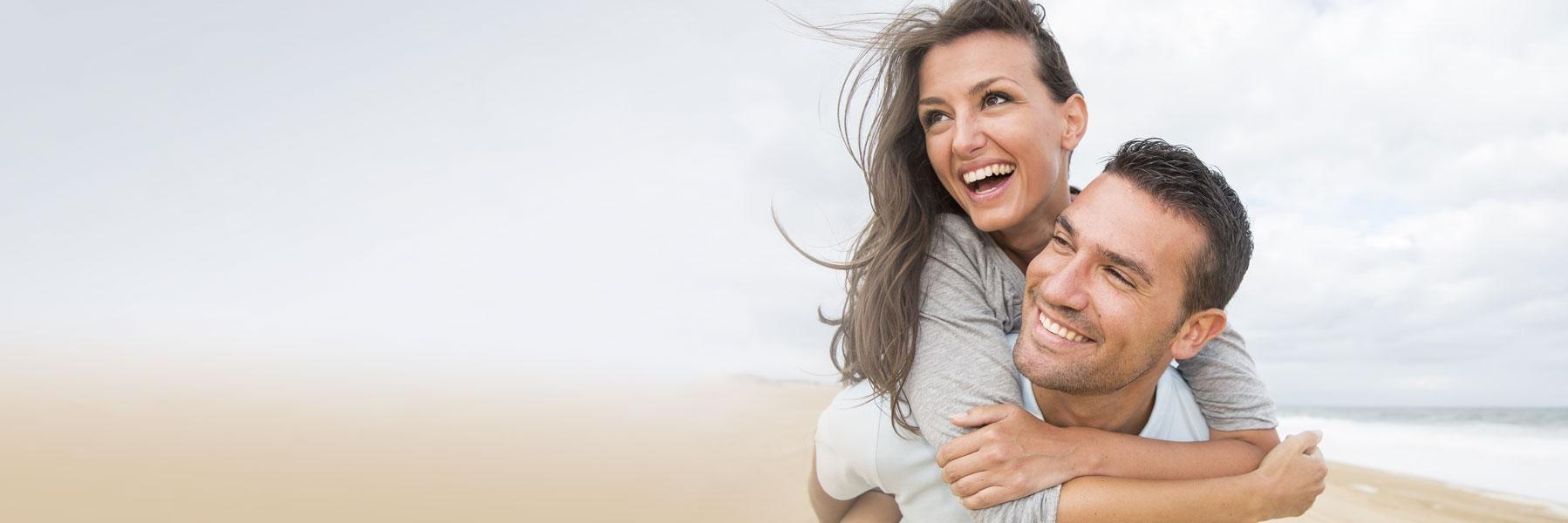 young couple smiling on beach l top dentist wilmington