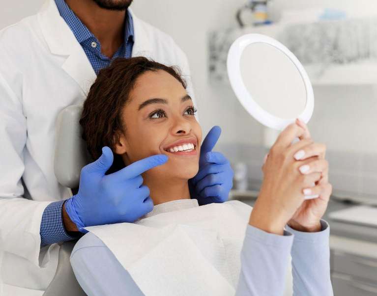 A dentist showing a woman her smile in the mirror 