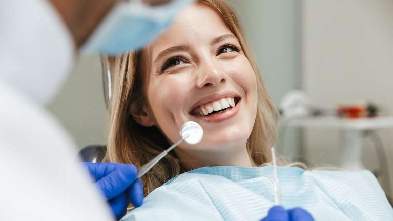 A smiling woman getting a dental exam in Wilmington