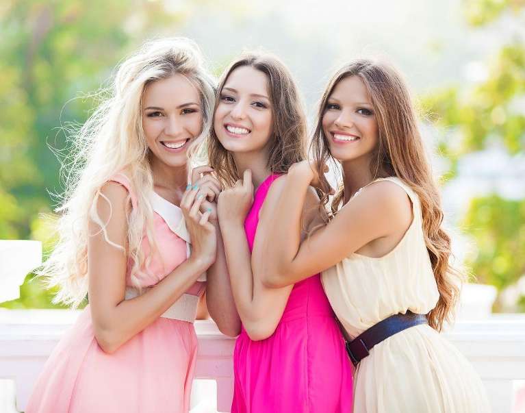 Three sisters posing on a balcony in dresses