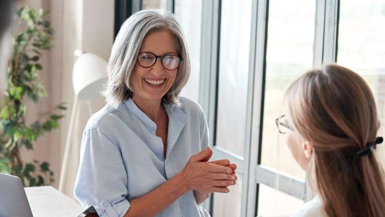 An older woman smiling in an office | oral health and aging Wilmington, DE
