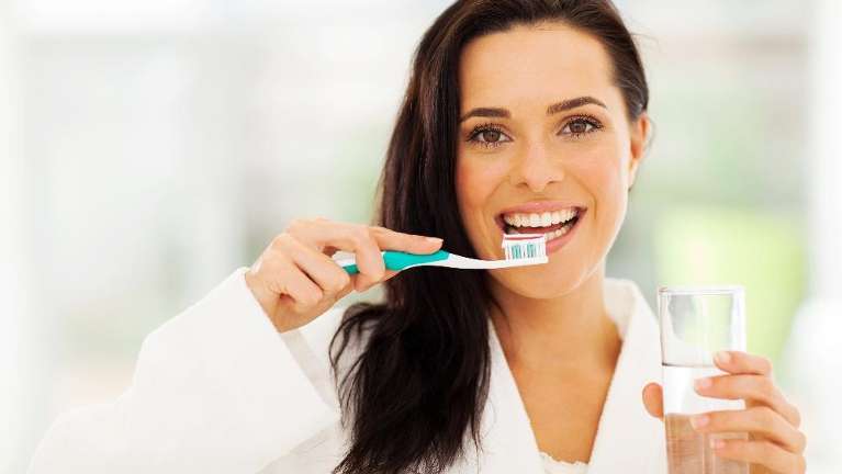 A smiling woman brushing her teeth for dental hygiene in Wilmington, DE
