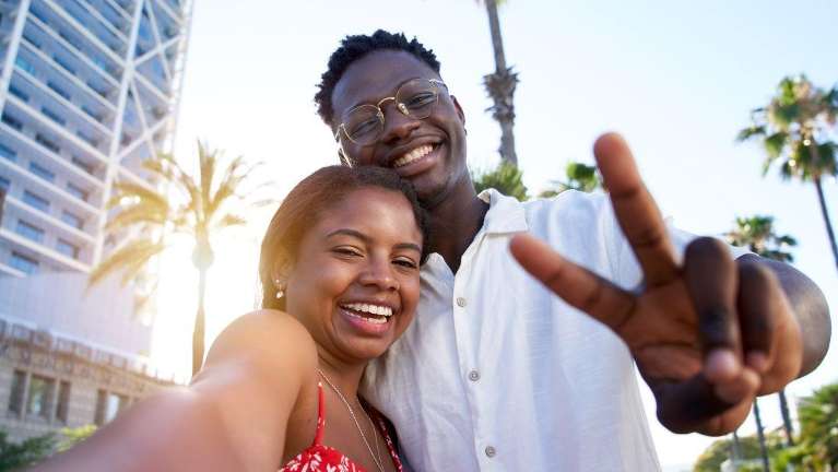 A couple smiling in front of palm trees | cosmetic dentist Wilmington, DE