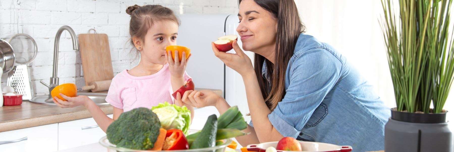 A mother and daughter eating fruits and vegetables