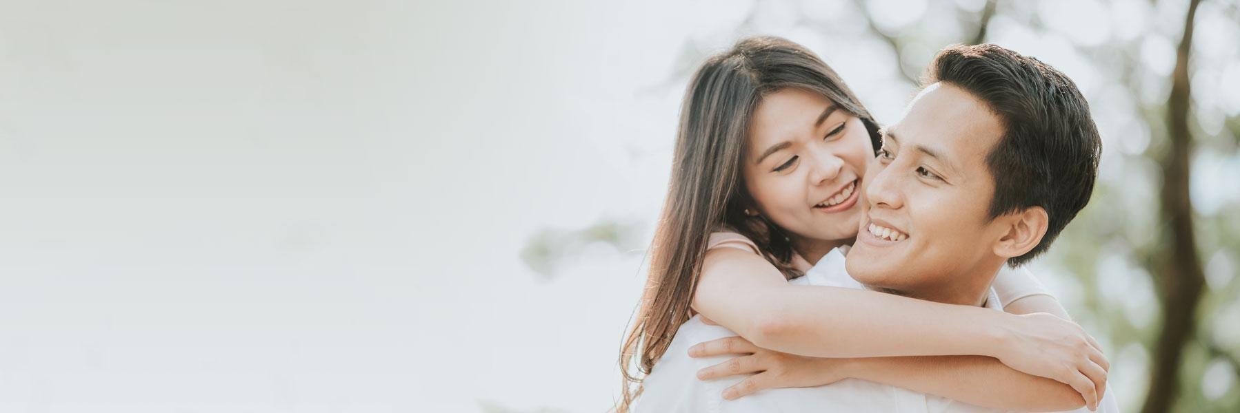 asian couple hugging & smiling l tooth-colored fillings wilmington