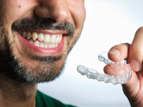 man holds Invisalign clear aligner
